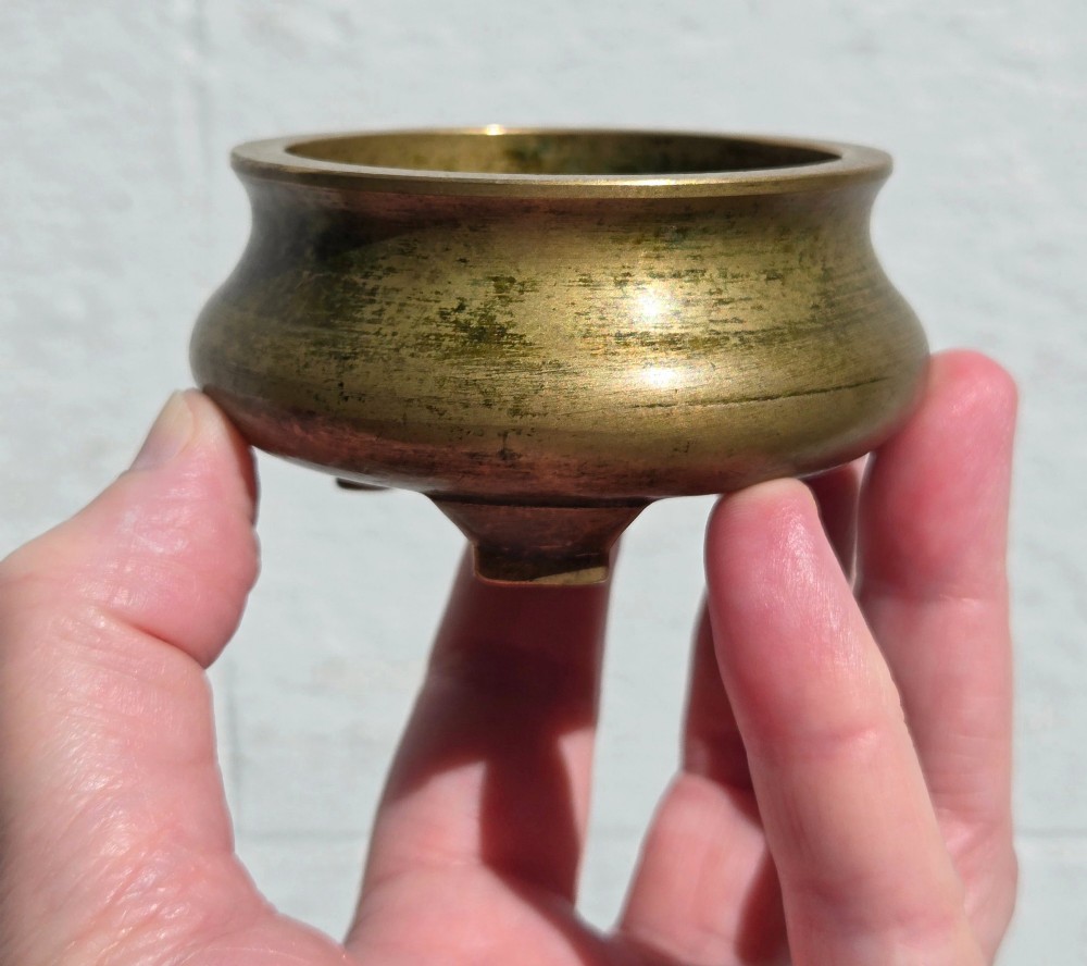 Underside view of a heavy bronze tripod censer displaying three short feet and a square recessed seal mark filled with turquoise oxidisation. View VI