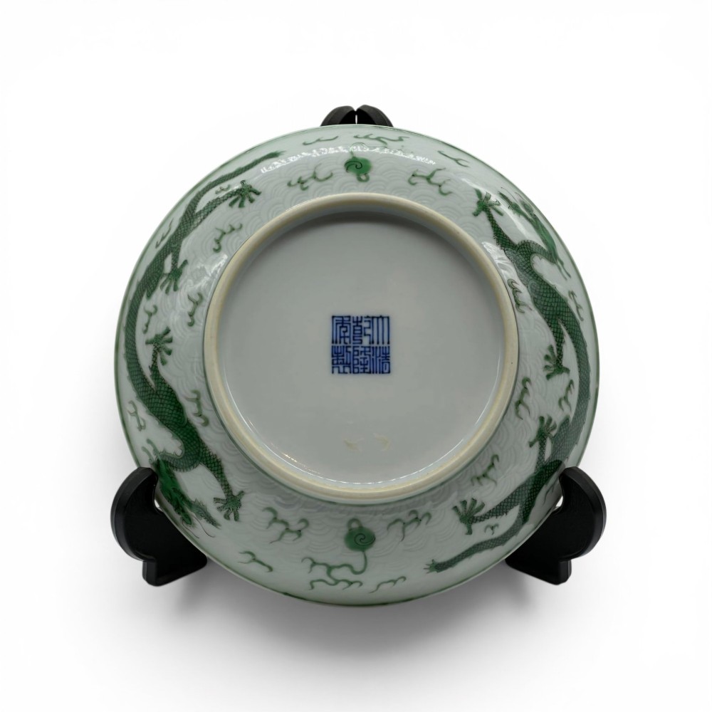A circular white porcelain dish featuring a central green five-clawed dragon painted in overglaze enamel amidst stylised flames. View II