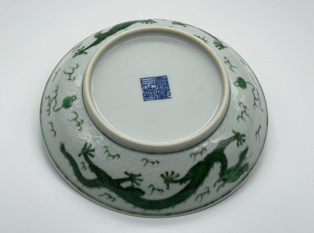 A circular white porcelain dish featuring a central green five-clawed dragon painted in overglaze enamel amidst stylised flames. View VIII