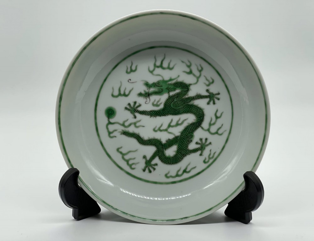A circular white porcelain dish featuring a central green five-clawed dragon painted in overglaze enamel amidst stylised flames. View XI
