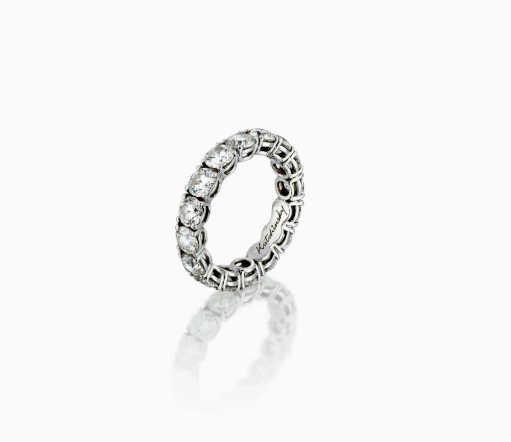 A platinum full eternity ring set with round brilliant diamonds, displayed inside its original black leather Kutchinsky box. View V