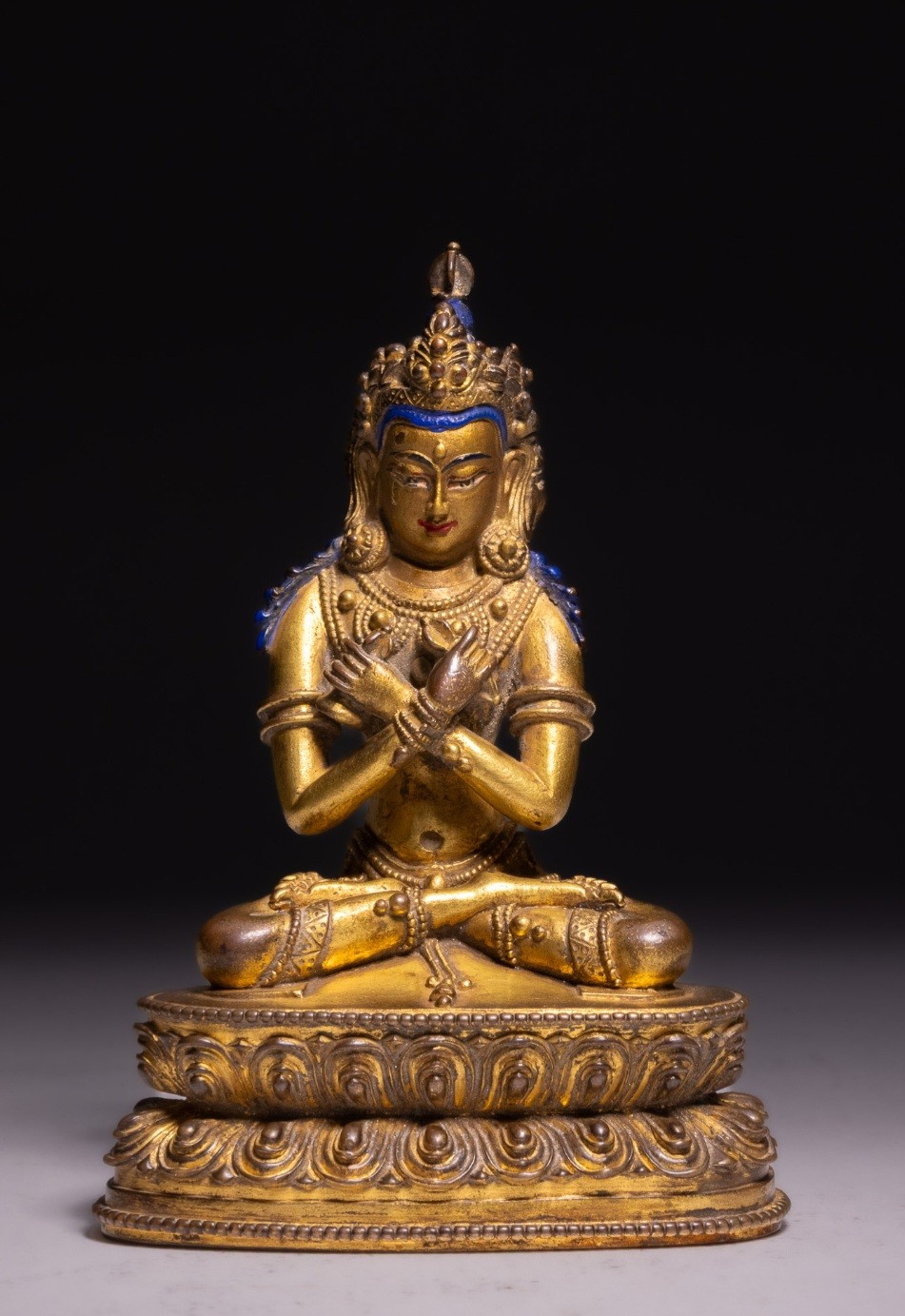 An 18th-century Sino-Tibetan gilt-bronze figure depicting the deity Vajradhara seated in meditation upon a double lotus pedestal.