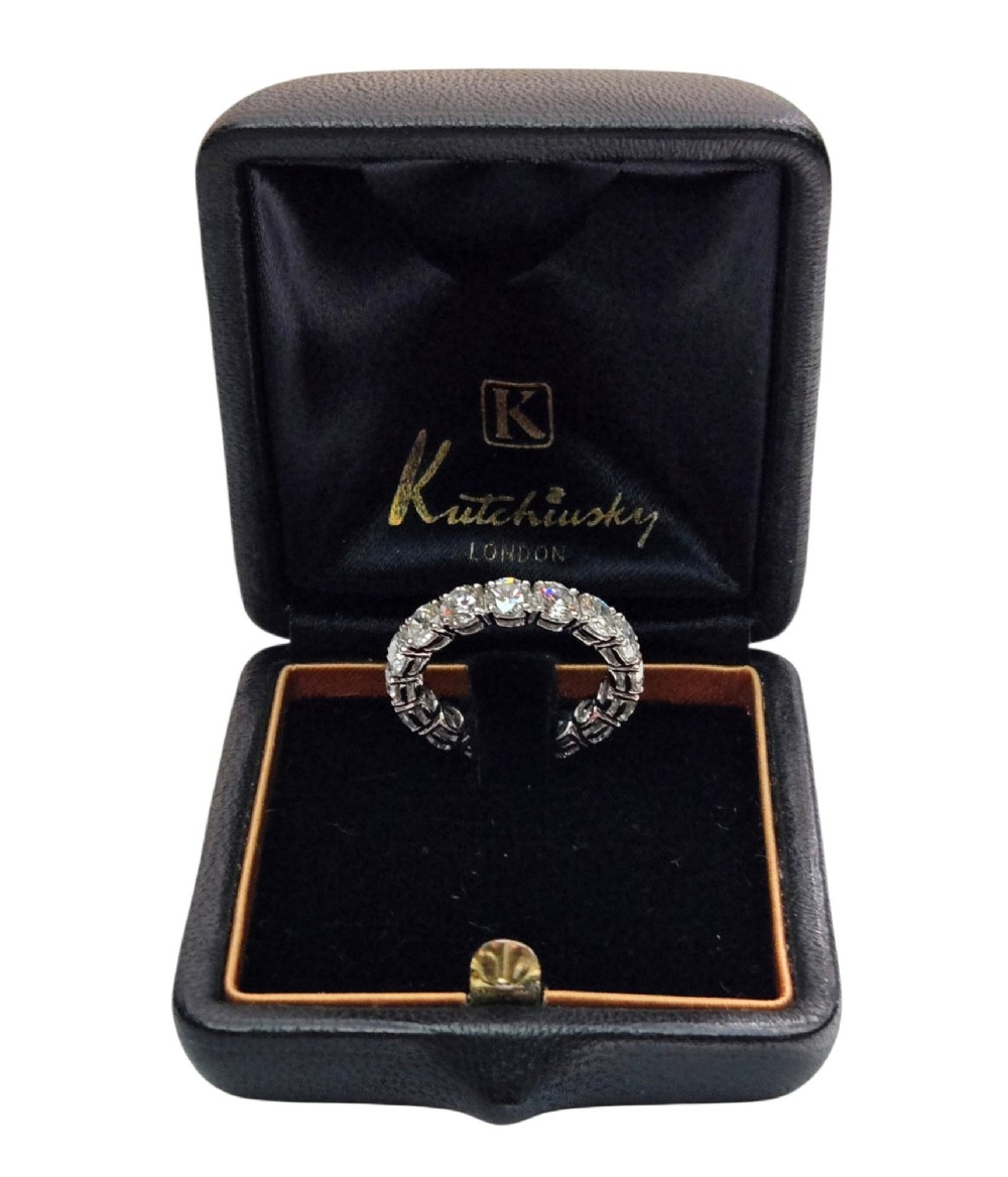 A platinum full eternity ring set with round brilliant diamonds, displayed inside its original black leather Kutchinsky box. View XI