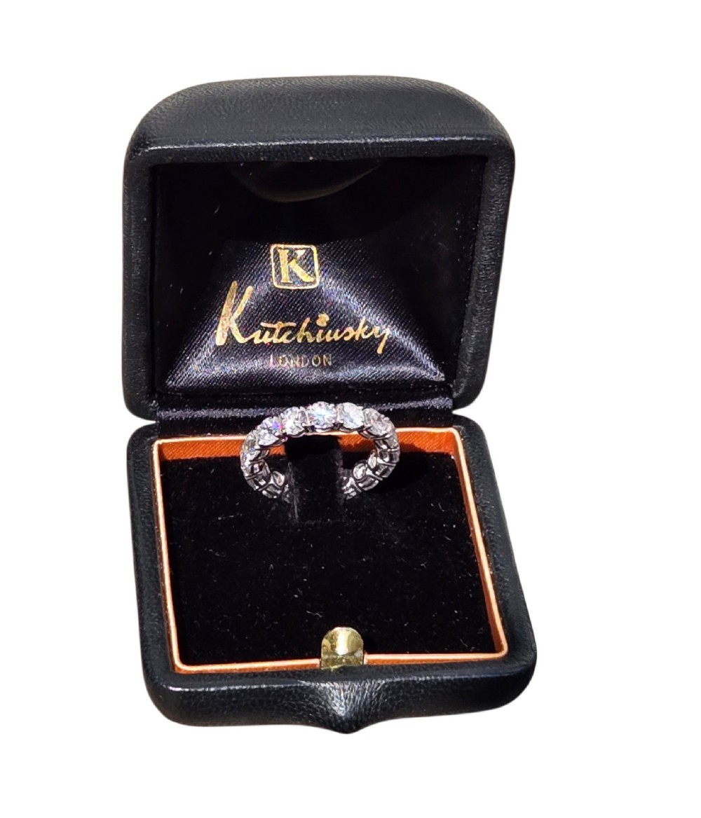 A platinum full eternity ring set with round brilliant diamonds, displayed inside its original black leather Kutchinsky box. View XII