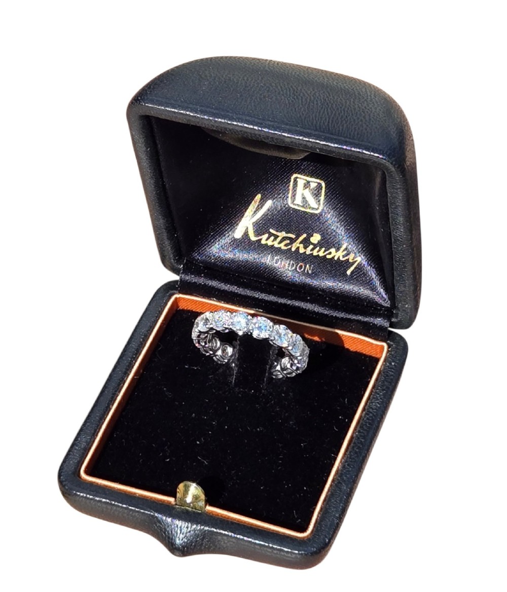 A platinum full eternity ring set with round brilliant diamonds, displayed inside its original black leather Kutchinsky box. View XIII
