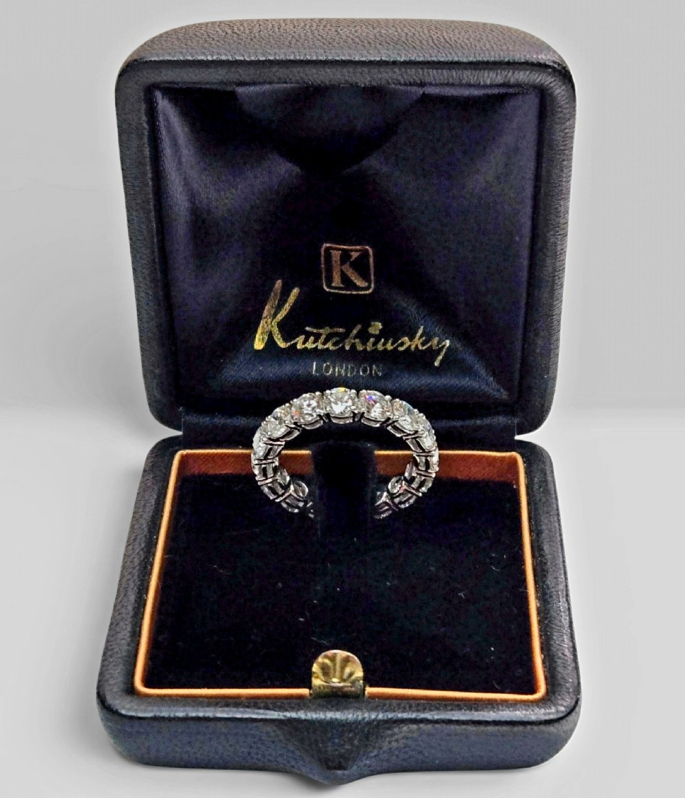 A platinum full eternity ring set with round brilliant diamonds, displayed inside its original black leather Kutchinsky box.