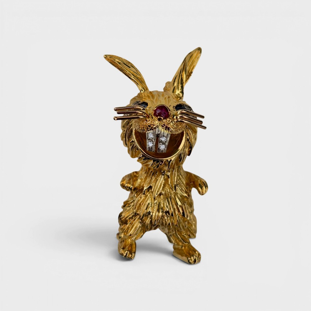 An 18ct yellow gold rabbit brooch showcasing textured fur detailing, a ruby nose, diamond-set teeth, and sapphire eyes. View II