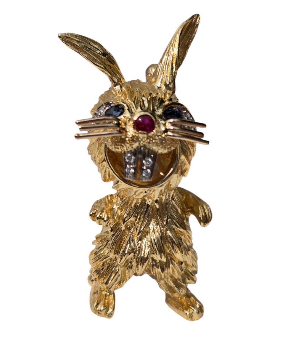 An 18ct yellow gold rabbit brooch showcasing textured fur detailing, a ruby nose, diamond-set teeth, and sapphire eyes. View III