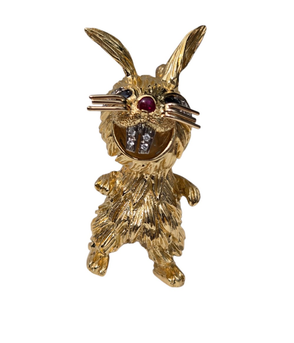 An 18ct yellow gold rabbit brooch showcasing textured fur detailing, a ruby nose, diamond-set teeth, and sapphire eyes. View VIII
