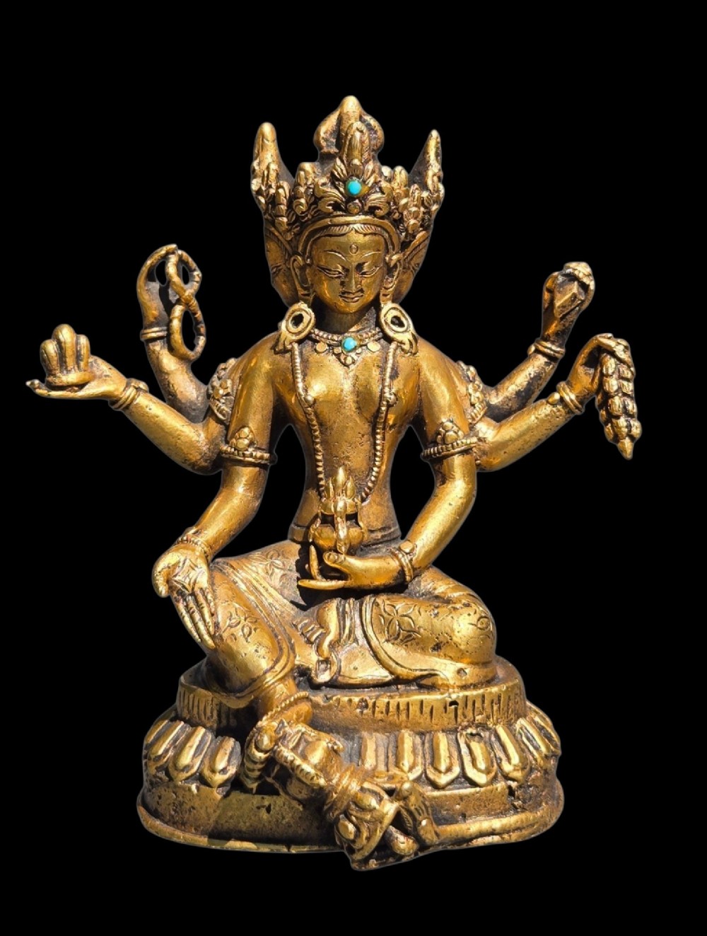 An early 19th-century gilt bronze multi-armed deity figure seated on a lotus base with turquoise stone inlays in the crown.