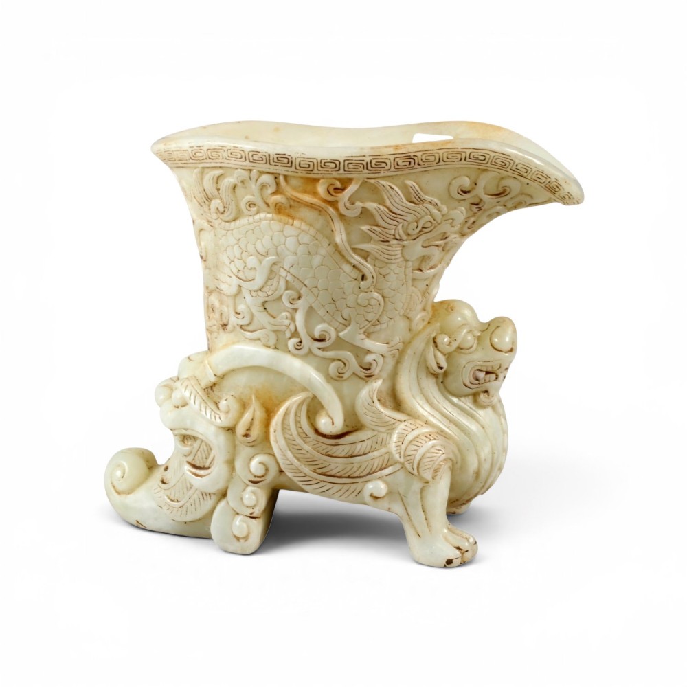 A carved pale celadon nephrite jade rhyton cup featuring relief dragon and mythical beast motifs with subtle russet inclusions. View XI