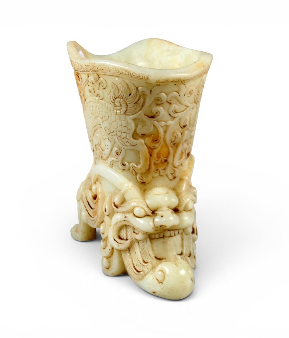 A carved pale celadon nephrite jade rhyton cup featuring relief dragon and mythical beast motifs with subtle russet inclusions. View XIII