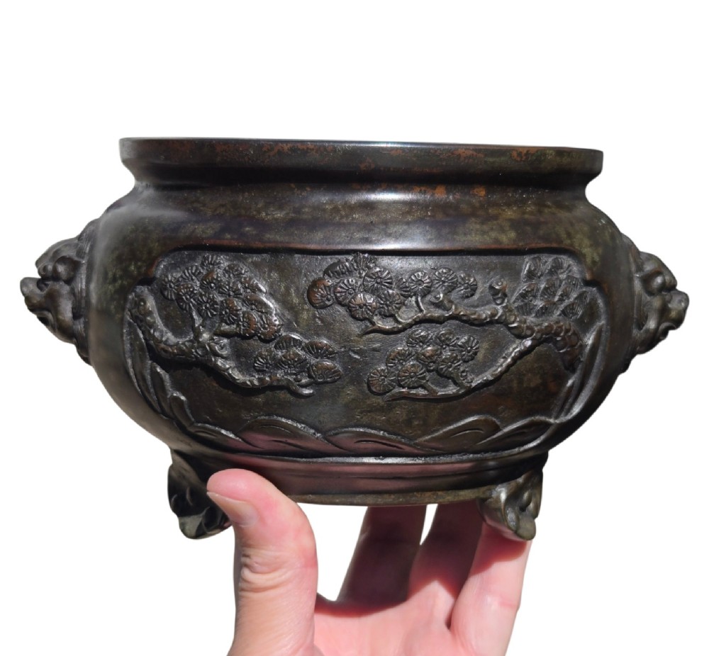 A dark patinated cast bronze incense burner featuring raised relief panels of bamboo and beast mask side handles. View V