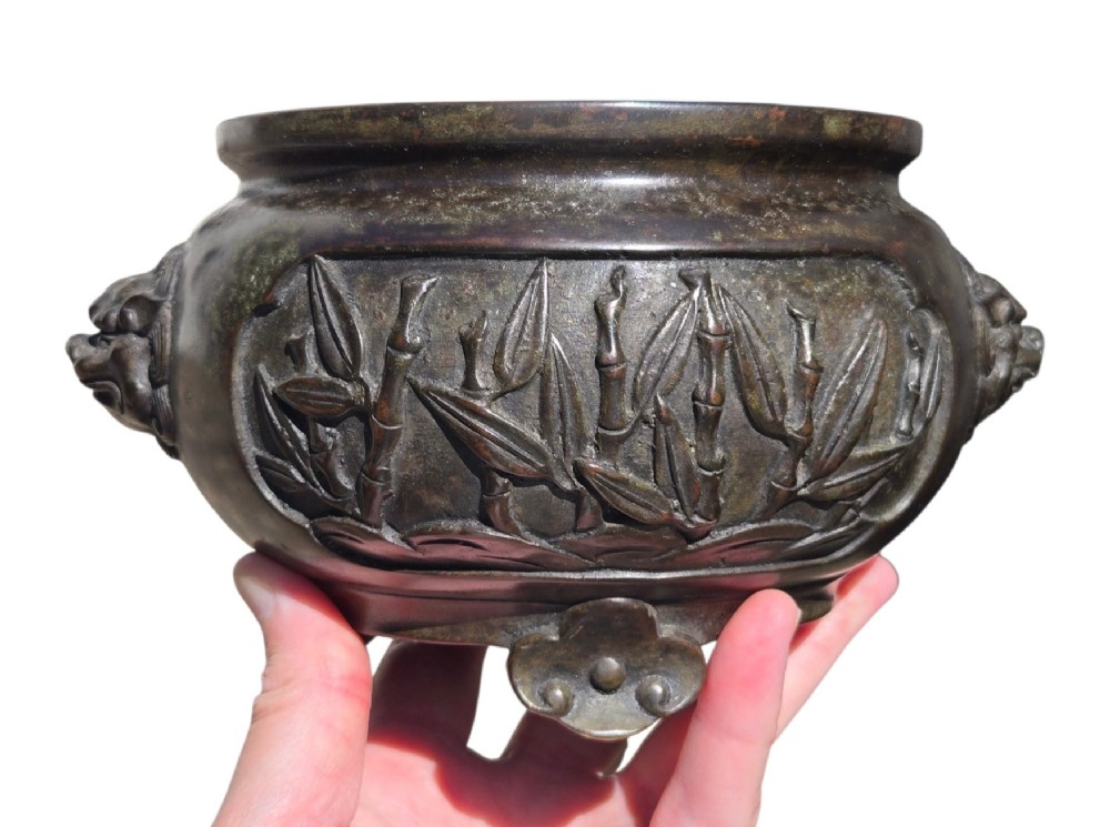 A dark patinated cast bronze incense burner featuring raised relief panels of bamboo and beast mask side handles. View VIII