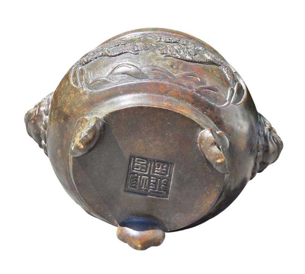 A dark patinated cast bronze incense burner featuring raised relief panels of bamboo and beast mask side handles. View IX
