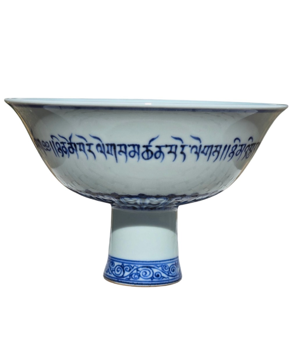A Chinese blue and white porcelain stem cup featuring Tibetan script around the exterior flared bowl and a hollow cylindrical foot. View III