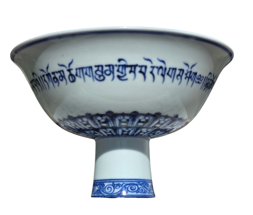 A Chinese blue and white porcelain stem cup featuring Tibetan script around the exterior flared bowl and a hollow cylindrical foot. View VII