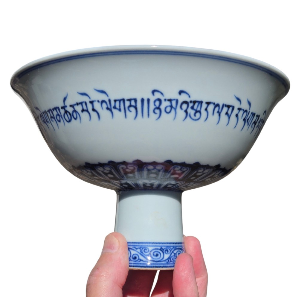 A Chinese blue and white porcelain stem cup featuring Tibetan script around the exterior flared bowl and a hollow cylindrical foot. View XII