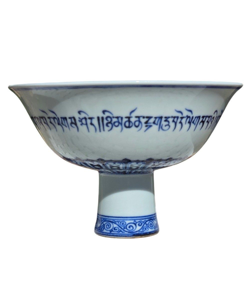 A Chinese blue and white porcelain stem cup featuring Tibetan script around the exterior flared bowl and a hollow cylindrical foot. View XIII