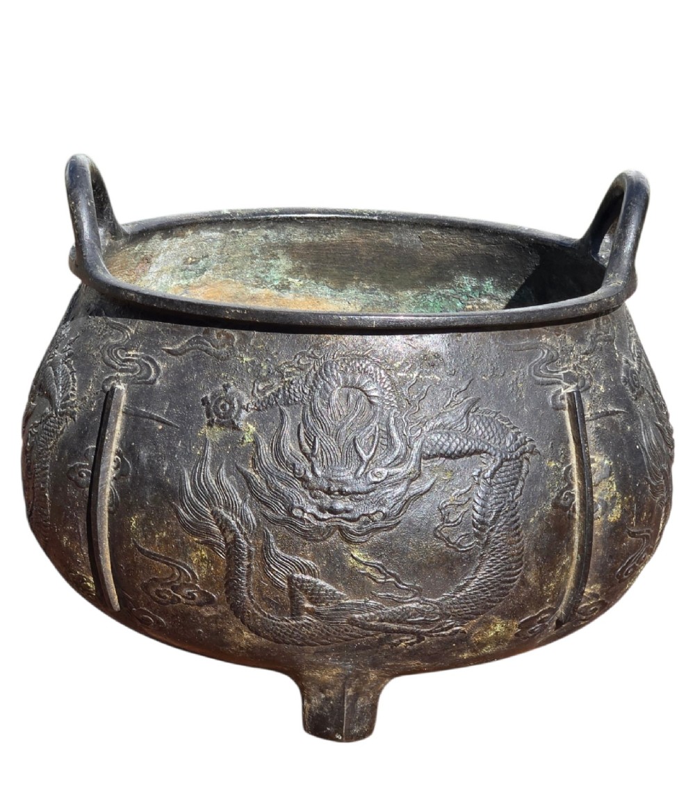 A dark cast bronze tripod censer with loop handles, low feet, and dragon motifs in relief across the exterior. View III