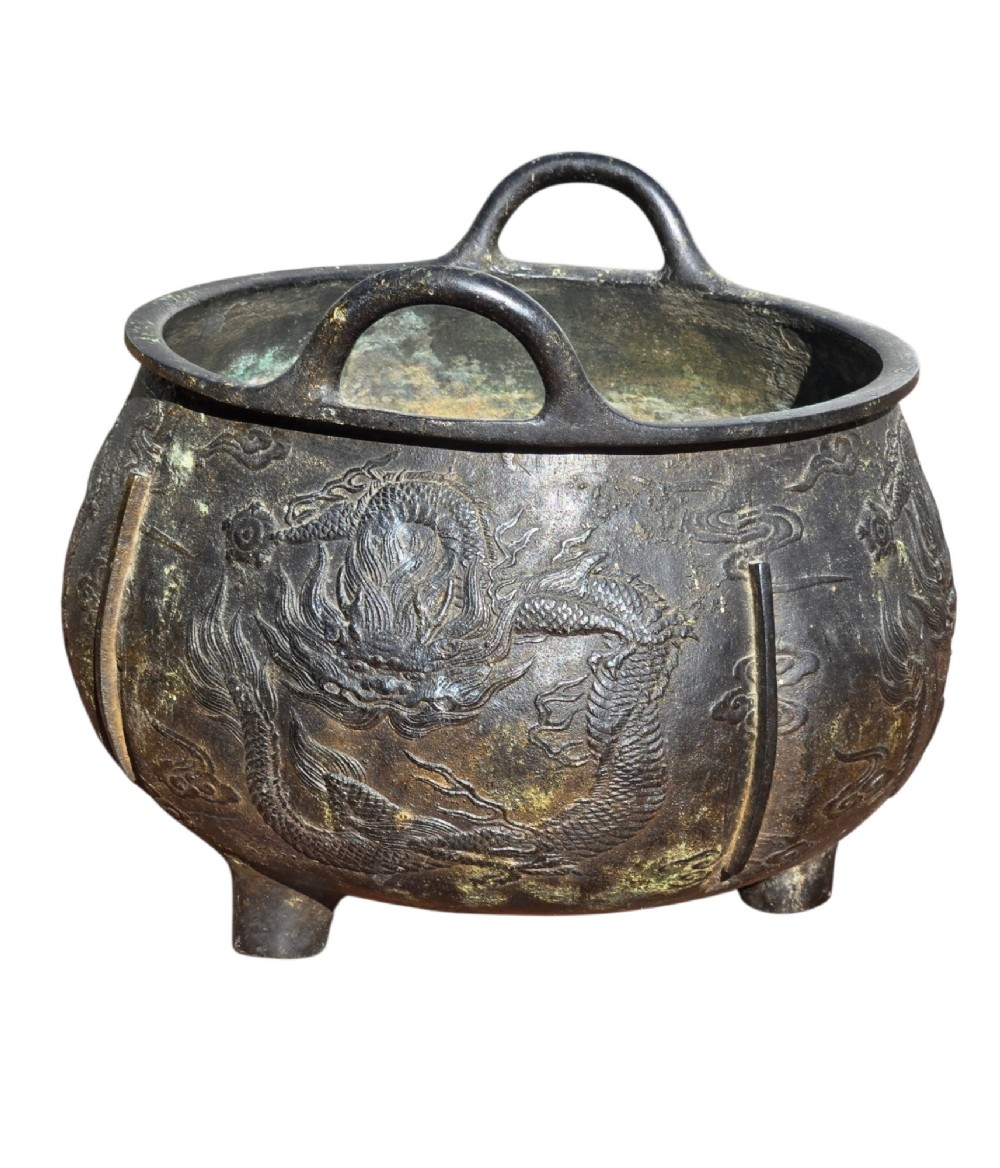 A dark cast bronze tripod censer with loop handles, low feet, and dragon motifs in relief across the exterior. View V
