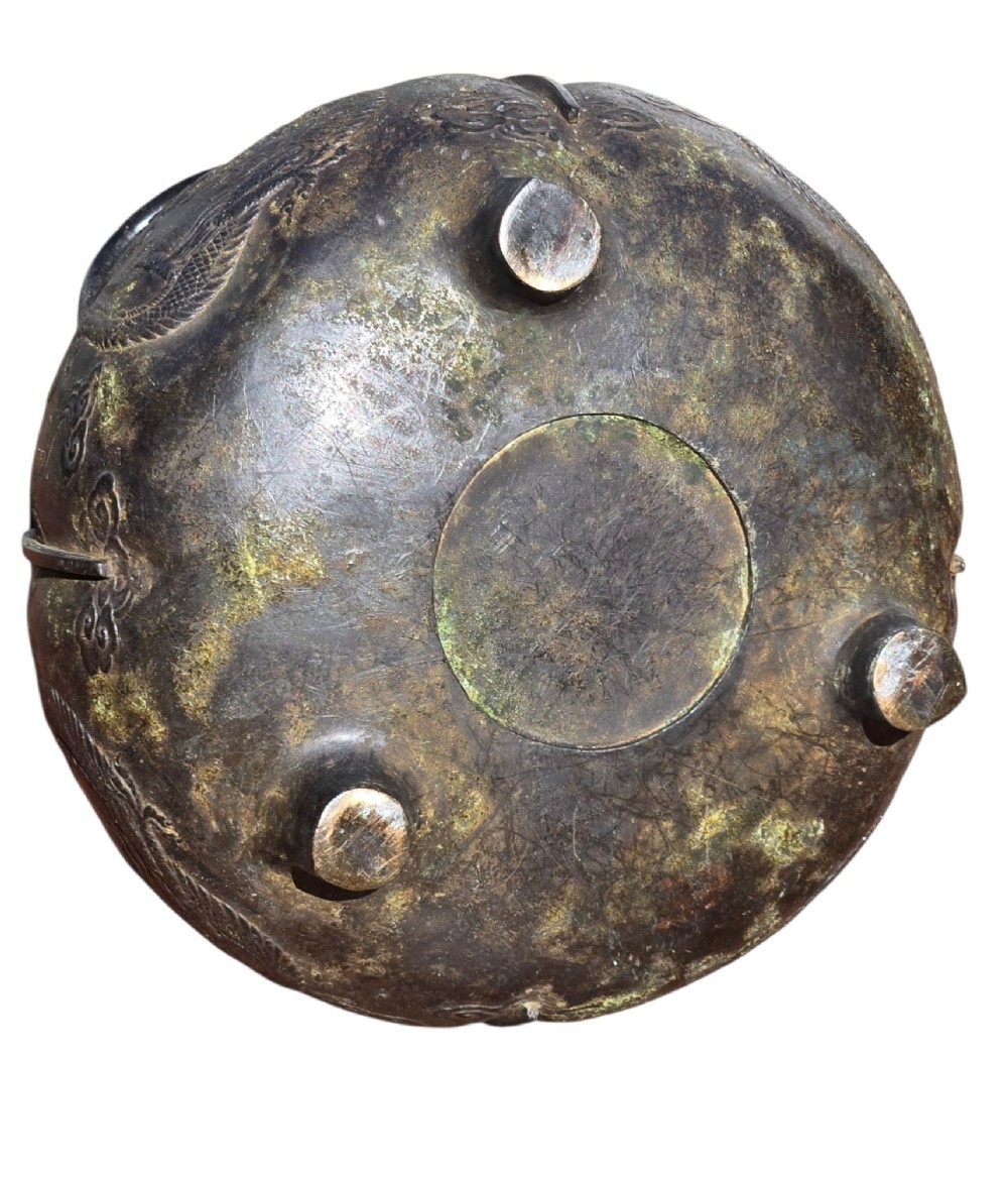 A dark cast bronze tripod censer with loop handles, low feet, and dragon motifs in relief across the exterior. View IX