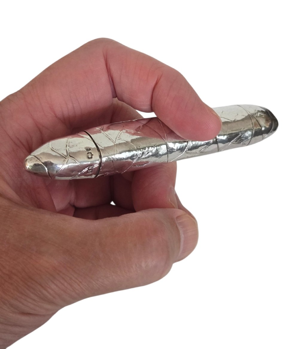 A Victorian sterling silver vesta case crafted in the shape of a double-ended cigar with engraved leaf textures.