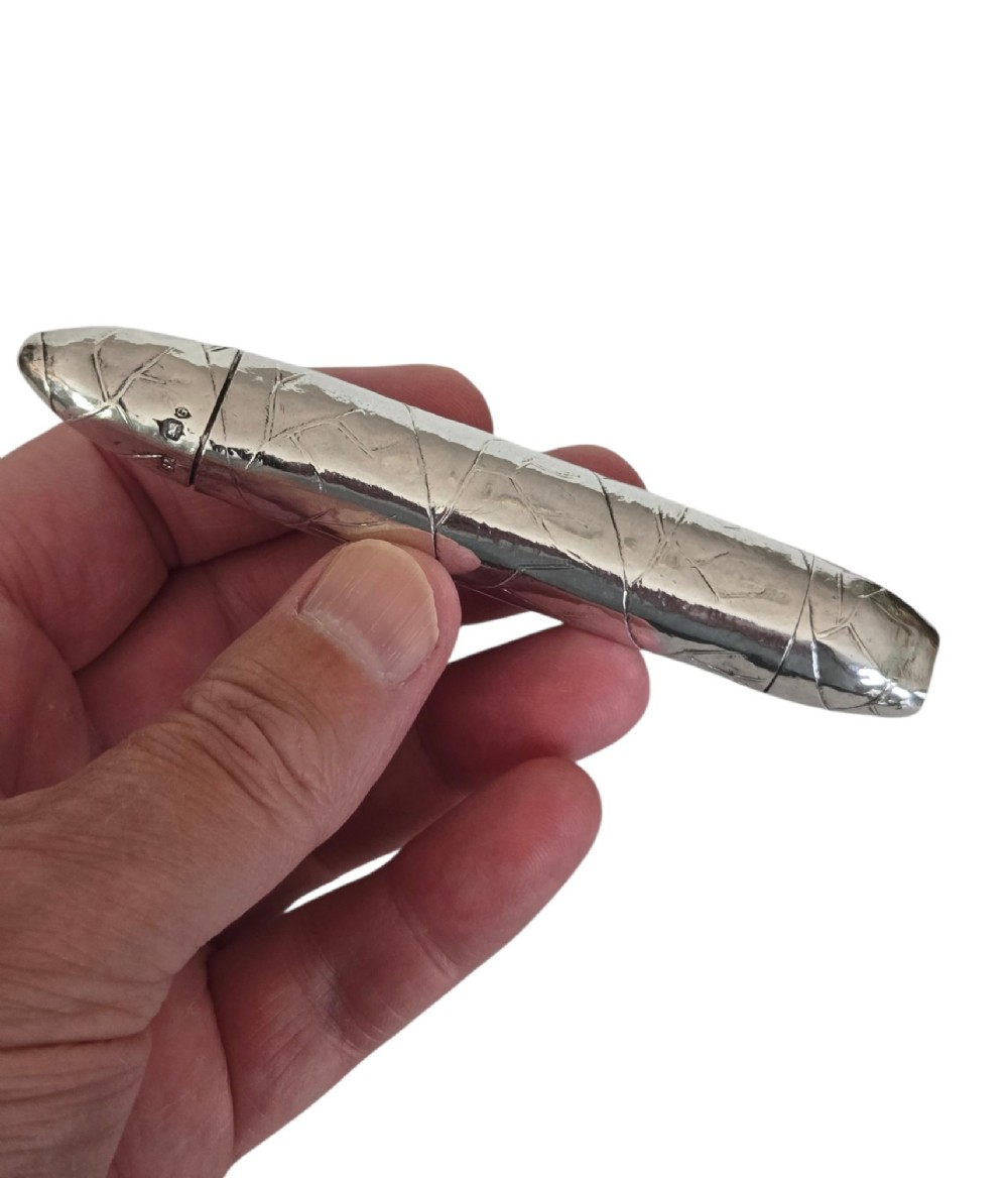 A Victorian sterling silver vesta case crafted in the shape of a double-ended cigar with engraved leaf textures. View V