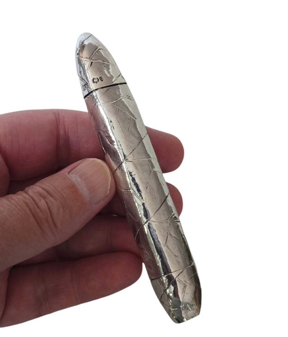 A Victorian sterling silver vesta case crafted in the shape of a double-ended cigar with engraved leaf textures. View VI