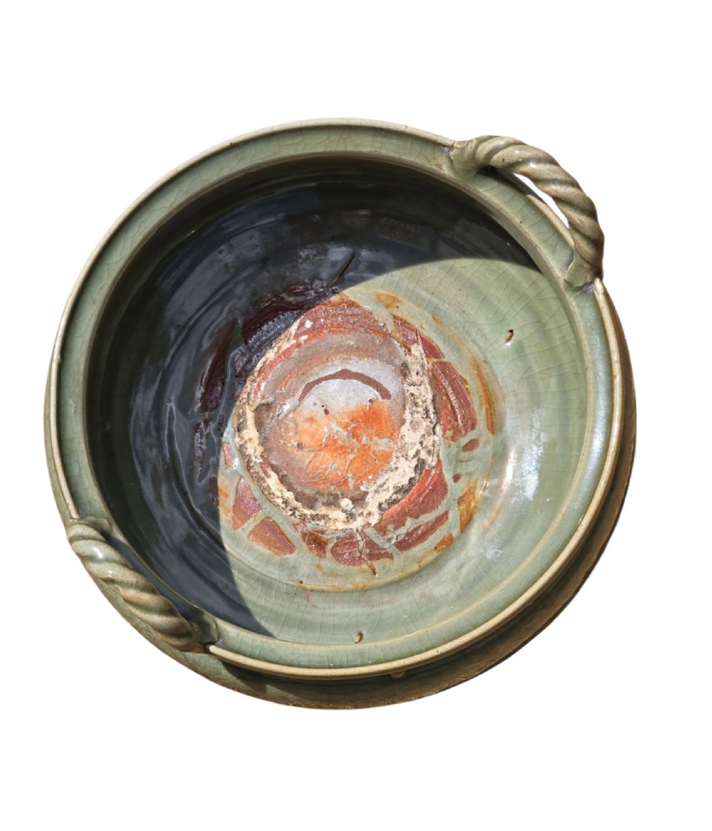 A green glazed Longquan celadon tripod censer with carved floral scrollwork beneath the glaze, twin rope-twist handles, and three mask feet. View XI