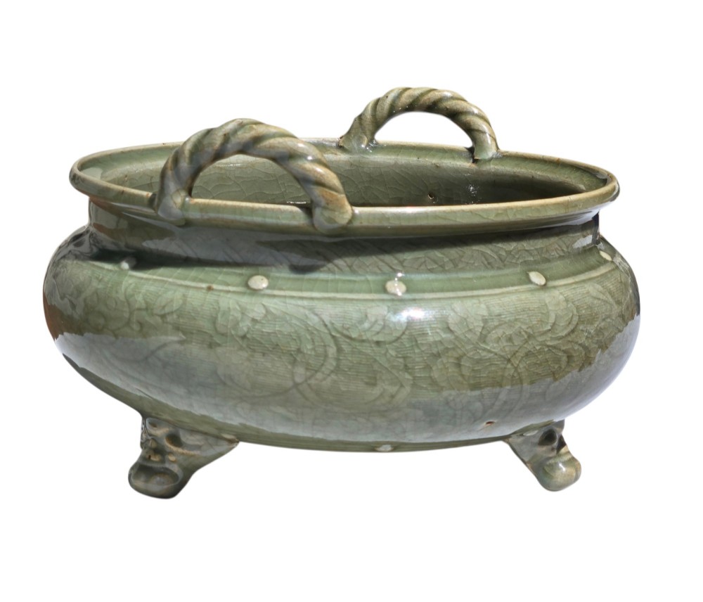 A green glazed Longquan celadon tripod censer with carved floral scrollwork beneath the glaze, twin rope-twist handles, and three mask feet. View XIII