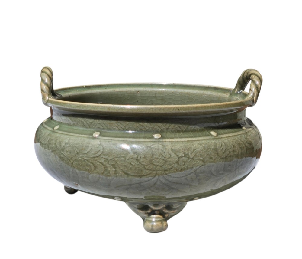 A green glazed Longquan celadon tripod censer with carved floral scrollwork beneath the glaze, twin rope-twist handles, and three mask feet. View XV