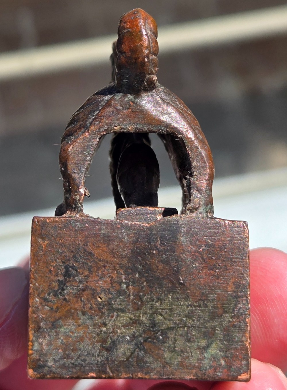 A cast bronze Chinese seal featuring a qilin finial resting atop a square base with reddish brown patination. View X