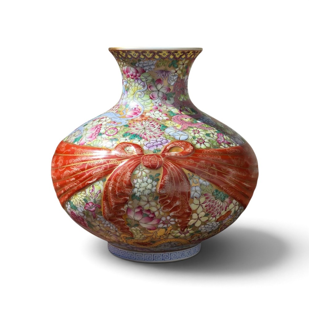 A spherical porcelain vase decorated with a dense millefleurs floral pattern, dual dragon motifs, a tied iron-red ribbon motif, and a turquoise interior rim.