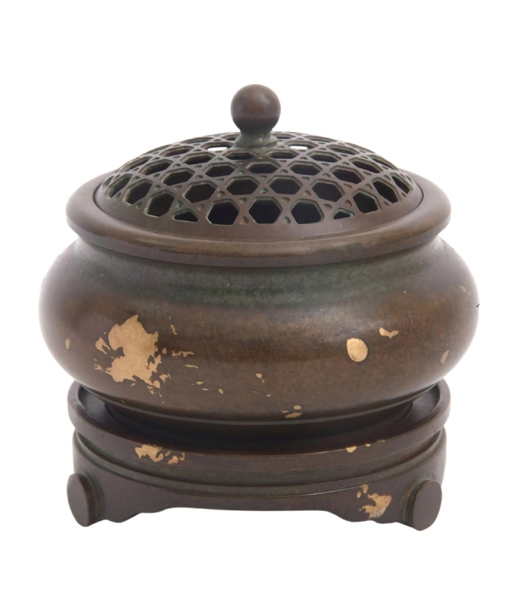 A dark brown bronze circular censer featuring gold splash decoration, a reticulated lattice cover with a spherical finial, and a matching footed bronze stand. View VII