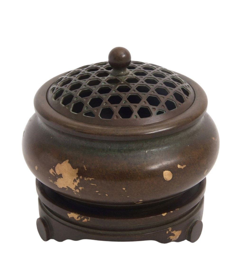A dark brown bronze circular censer featuring gold splash decoration, a reticulated lattice cover with a spherical finial, and a matching footed bronze stand. View X