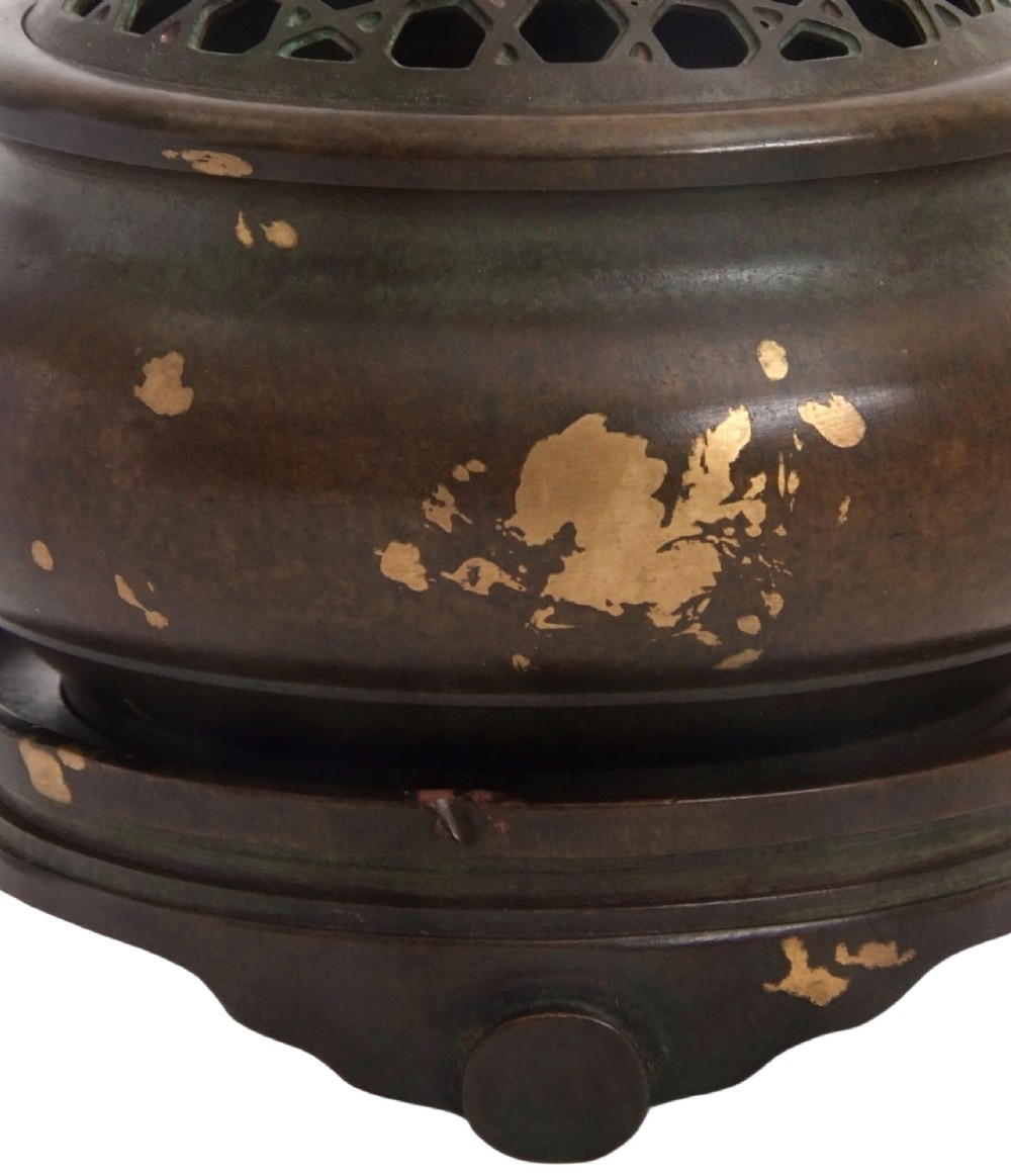 A dark brown bronze circular censer featuring gold splash decoration, a reticulated lattice cover with a spherical finial, and a matching footed bronze stand. View XIII