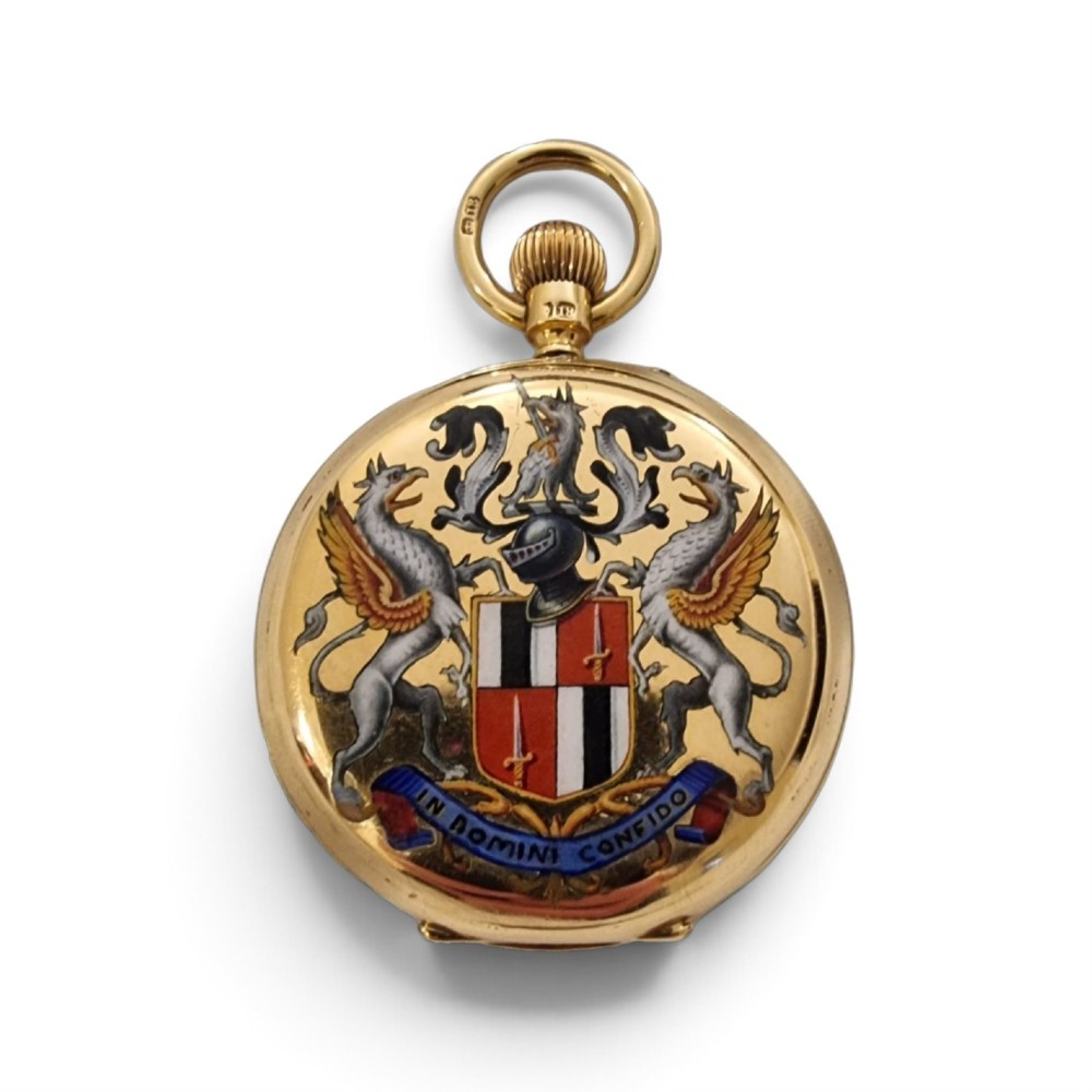 An 18-karat gold Victorian pocket watch casing displaying a polychrome enamelled coat of arms flanked by griffin supporters and a heraldic motto banner. View II