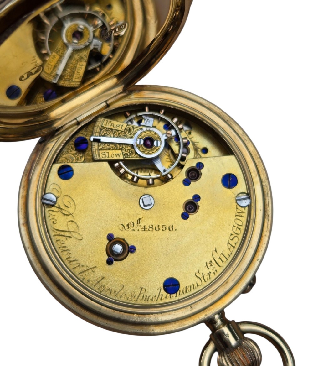 An 18-karat gold Victorian pocket watch casing displaying a polychrome enamelled coat of arms flanked by griffin supporters and a heraldic motto banner. View V