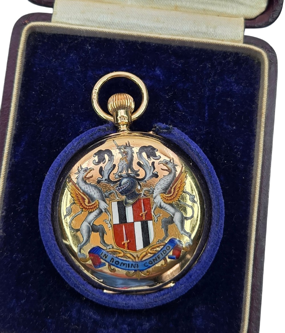 An 18-karat gold Victorian pocket watch casing displaying a polychrome enamelled coat of arms flanked by griffin supporters and a heraldic motto banner. View XIII