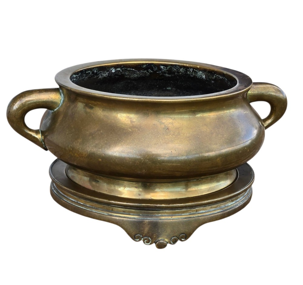 A heavy Chinese bronze ritual censer featuring twin loop handles and resting on a matching fitted base with shaped feet. View VI