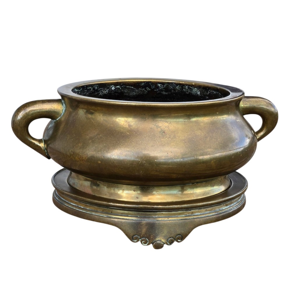 A heavy Chinese bronze ritual censer featuring twin loop handles and resting on a matching fitted base with shaped feet. View VII