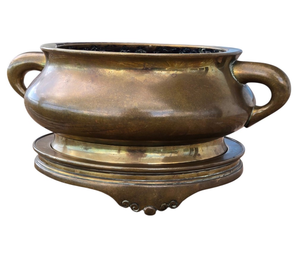 A heavy Chinese bronze ritual censer featuring twin loop handles and resting on a matching fitted base with shaped feet. View VIII