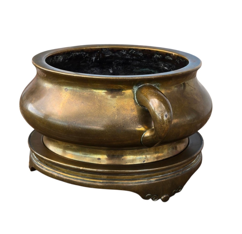A heavy Chinese bronze ritual censer featuring twin loop handles and resting on a matching fitted base with shaped feet. View X