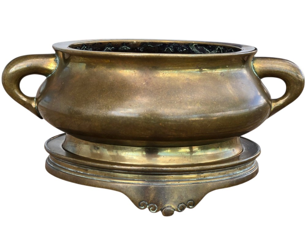 A heavy Chinese bronze ritual censer featuring twin loop handles and resting on a matching fitted base with shaped feet. View XIII