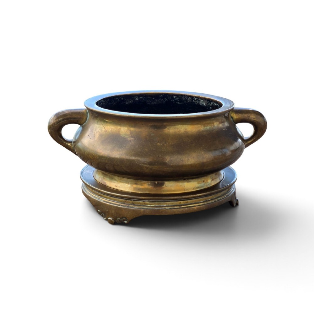 A heavy Chinese bronze ritual censer featuring twin loop handles and resting on a matching fitted base with shaped feet. View XIV