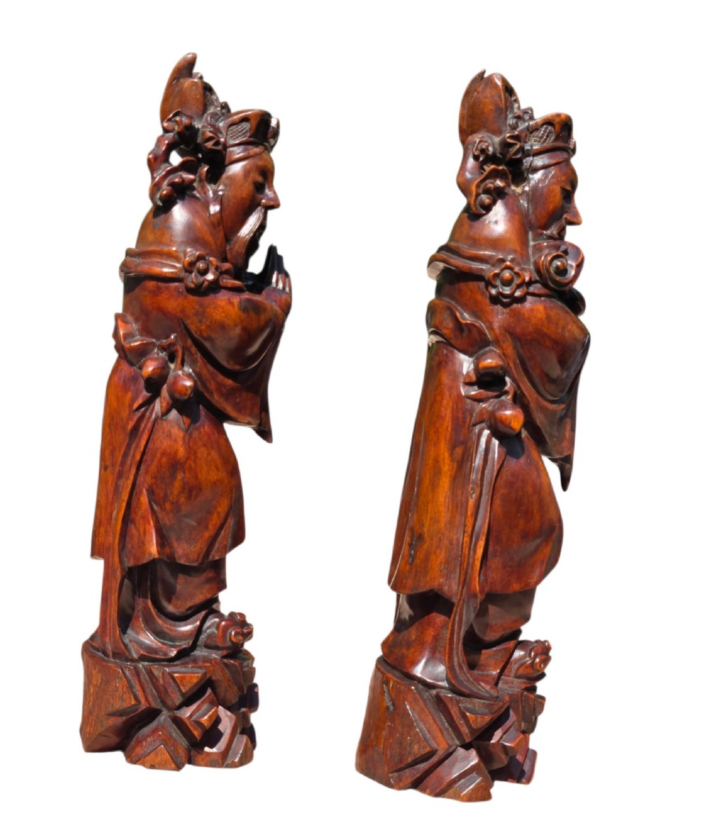 A pair of Chinese hardwood sculptures depicting Daoist immortals in flowing robes with carved geometric bases. View IX
