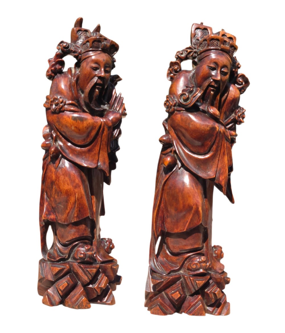 A pair of Chinese hardwood sculptures depicting Daoist immortals in flowing robes with carved geometric bases. View X