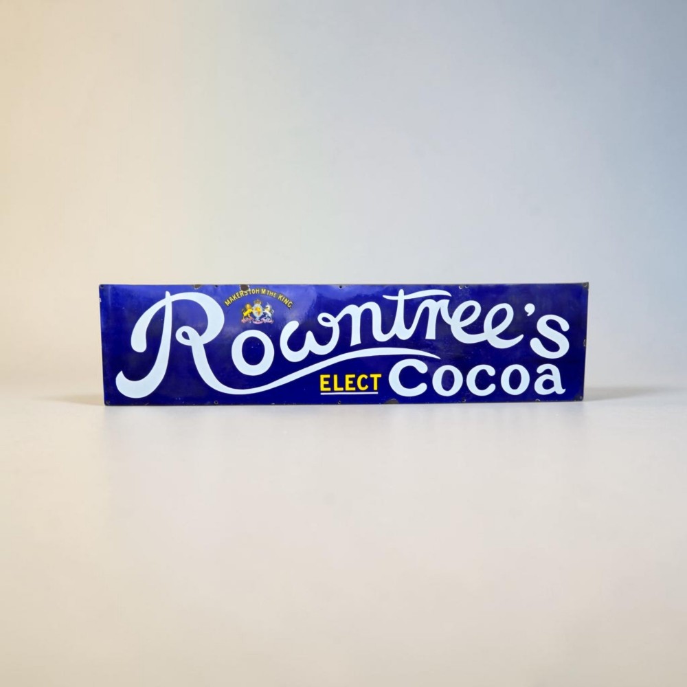 A rectangular cobalt blue vitreous enamel advertising sign featuring white script reading Rowntrees Cocoa and yellow lettering reading Elect Cocoa, topped with a royal warrant crest. View IV