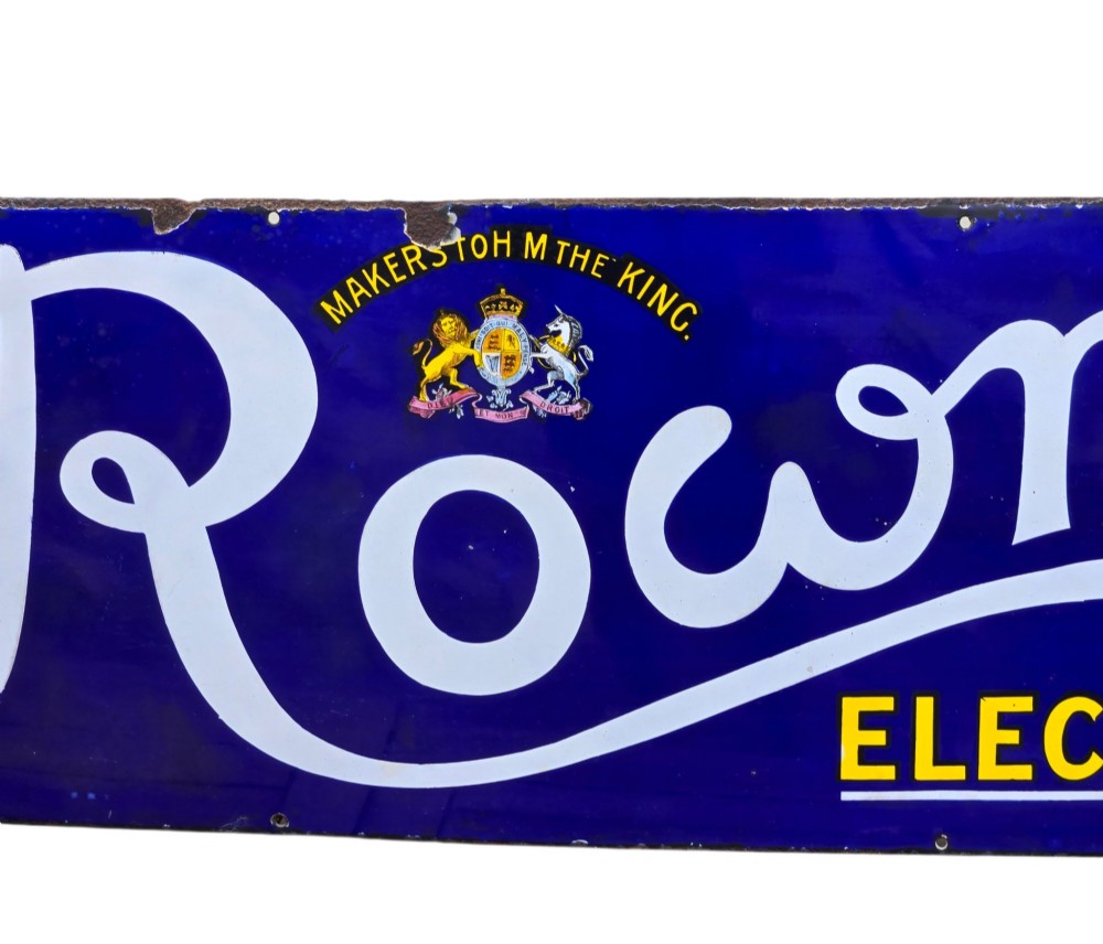 A rectangular cobalt blue vitreous enamel advertising sign featuring white script reading Rowntrees Cocoa and yellow lettering reading Elect Cocoa, topped with a royal warrant crest. View VI